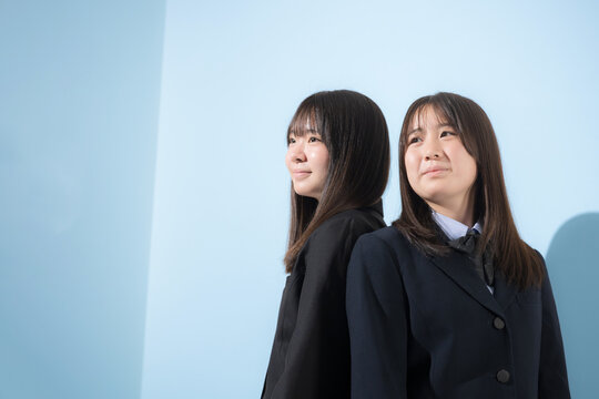 水色背景の未来を見つめて笑顔を見せる日本人女子高校生　2人で夢や進路を考える学校生活横顔のクローズアップ	