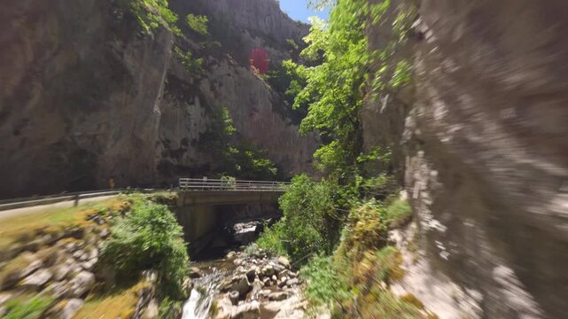 A fastpaced cinematic drone flight through a narrow limestone gorge with a mountain river and road. Captures the authentic natural beauty of Asturias, Spain.