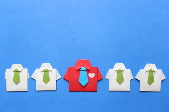Unique red shirt standing out among white shirts, business leadership and corporate team diversity concept, paper origami on blue background.