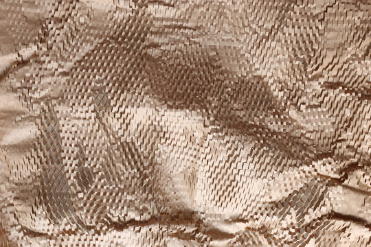 Eco-friendly honeycomb paper wrap, sustainable packaging material for protective shipping, abstract brown kraft paper texture background.