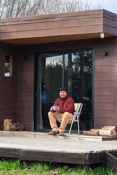 Cozy morning at a country house with a latino man drinking coffee on the wooden deck