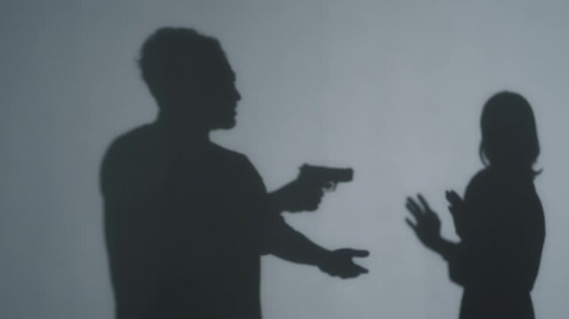 Silhouette of a man pointing a handgun at a woman. Robbery, crime, pistol, USA, gun culture, incident.