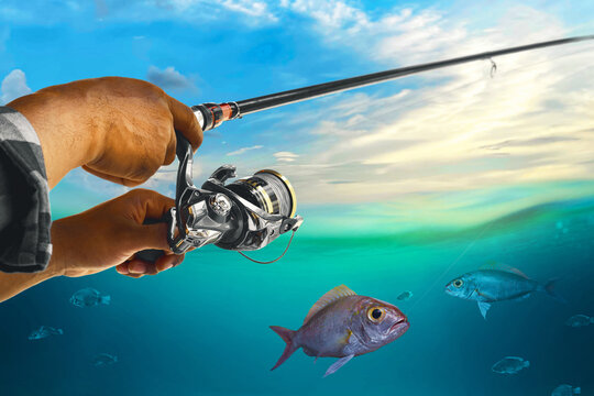 Closeup of hand holding fishing rod and catching fish underwater