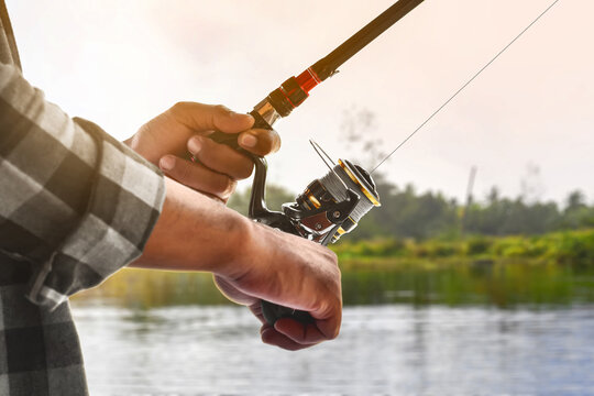 Closeup of hand holding fishing rod by lake