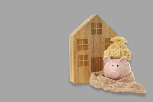 Warm piggy bank by wooden house in heating season