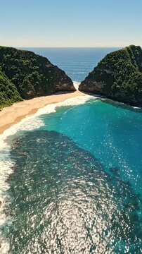 Aerial View of Hidden Beach Bay Turquoise Water - An aerial perspective reveals a secluded bay nestled between lush green cliffs, showcasing pristine golden sand and incredibly clear turquoise water.