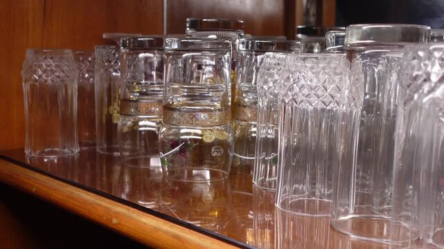 Clear glass cups on a wooden shelf in a kitchen