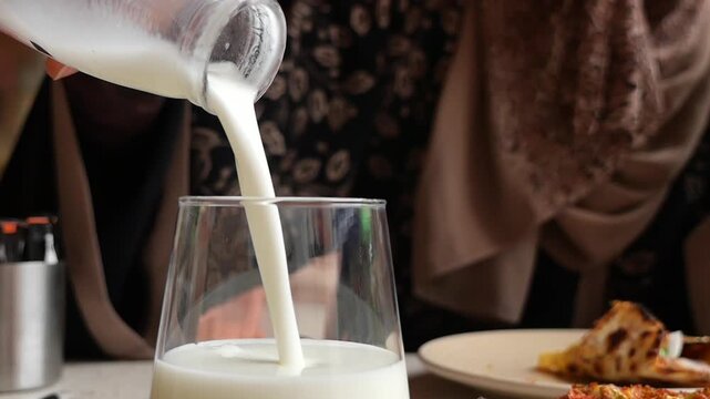 Pouring ayran into a glass at a cafe table