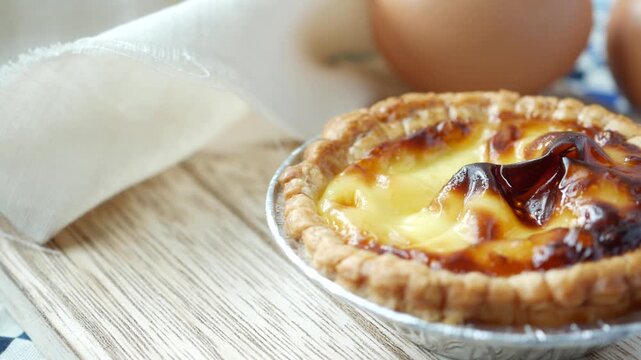 Close up motion footage of egg tart a delicious baked pastry with creamy custard filling on wooden surface