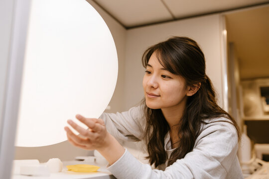 Soft light glows from round bulb beside her
