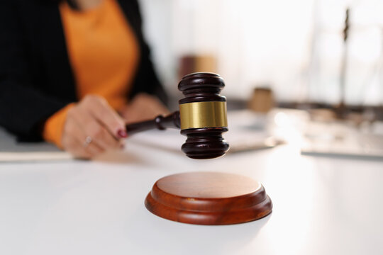 Hand holding wooden gavel preparing to strike or concluding a legal decision, symbolizing justice, law, judgment, authority, and official proceedings in a courtroom setting