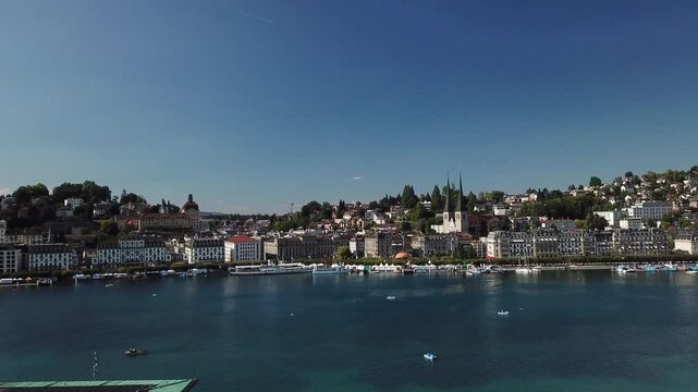 Smooth circular drone movement above KKL Luzern roof reveals churches, bayfront and lakeside city from an oblique angle