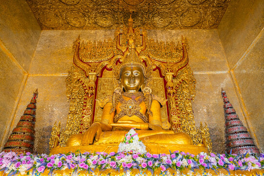 Magnificent golden Buddha statue inside the beautifully decorated pavilion at Wat Thai Wattanaram temple in Mae Sot, Tak, Thailand. A stunning example of sacred Mon Burmese art.