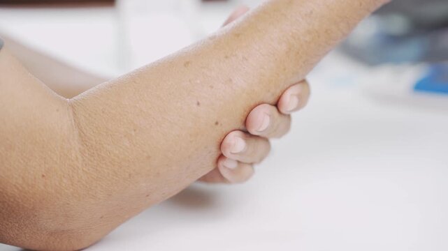 Close up of a senior holding a painful elbow, representing elbow pain, muscle strain, tendon inflammation, joint injury, rehabilitation, orthopedic care, chronic pain, and healthy aging.