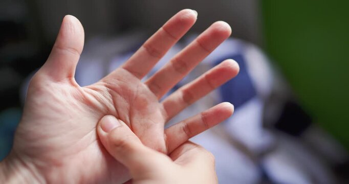Close-up of a person pressing and massaging their own palm to relieve hand discomfort and muscle tension. Self care, hand pain relief, finger flexibility, home rehabilitation, and wellness concept.