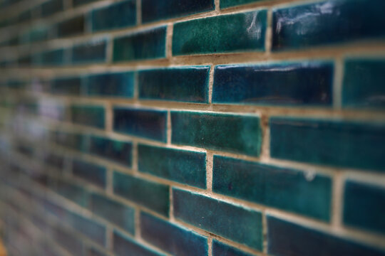 Close-up view of teal glossy brick wall tiles with beige grout
