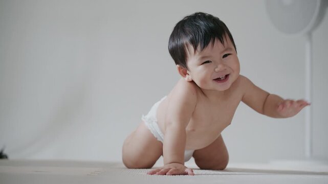 4K Cute Asian baby boy crawling on the floor and smiling happily.