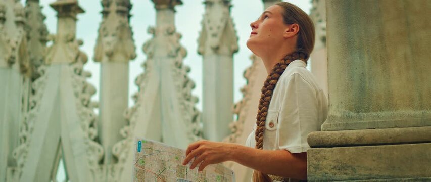 Woman admiring decorative gothic pillars while holding a map