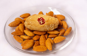 Fototapeta premium Side view of a single homemade sesame cookies in a included jam filled with almonds nuts on a glass plate, sweet cookies snacks, isolated on a white background.