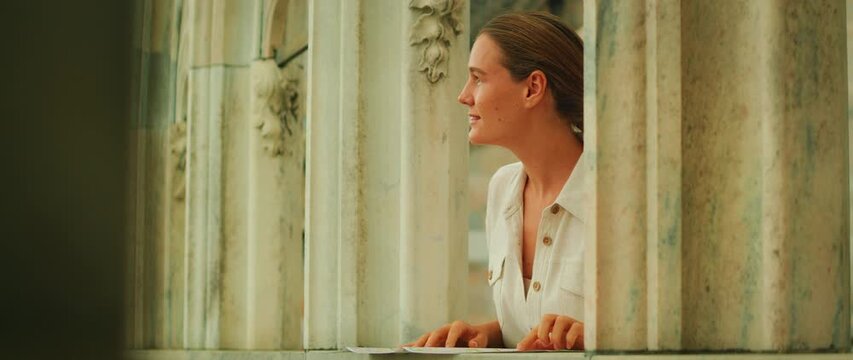 Woman leaning on marble railing and reading map inside stone cathedral structure