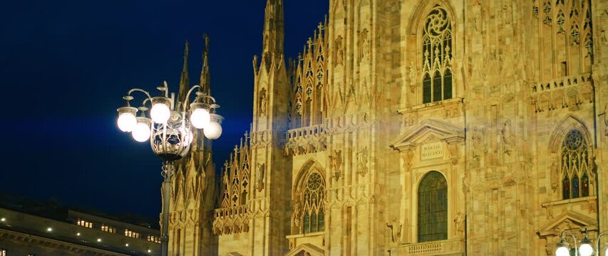 Milan Cathedral facade illuminated at night with gothic architectural elements