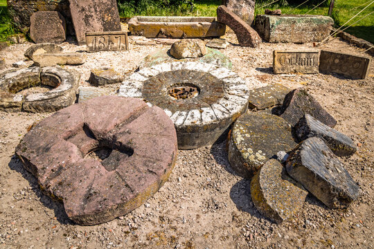 Collection of antique millstones and carved stone artifacts displayed outdoors