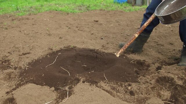 畑の土をふるう男性