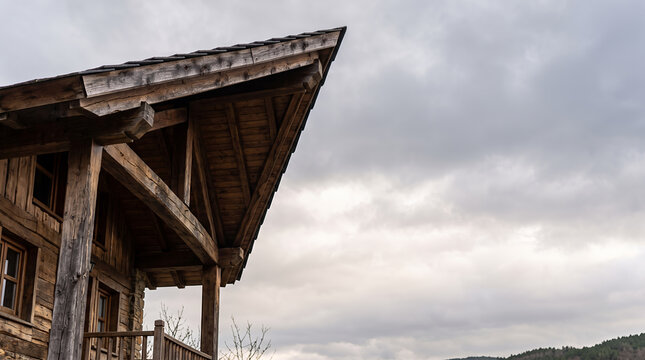 Rustic timber chalet eave and rafters silhouetted against an overcast grey sky