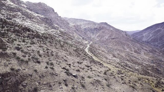 Aerial rocky ridge trail cutting through arid hills, textured slopes and winding dirt track suggest offbeat trekking route and outdoor adventure opportunities
