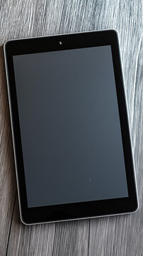Black tablet with blank screen on wooden surface