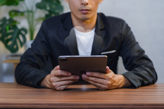 Young Man Using Tablet in Modern Indoor Setting with Green Plants Background