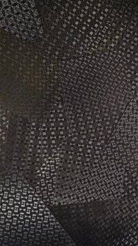 Vertical 4K video panning across overlapping dark cards with repeating geometric pattern, creating an abstract textured background with moody lighting.