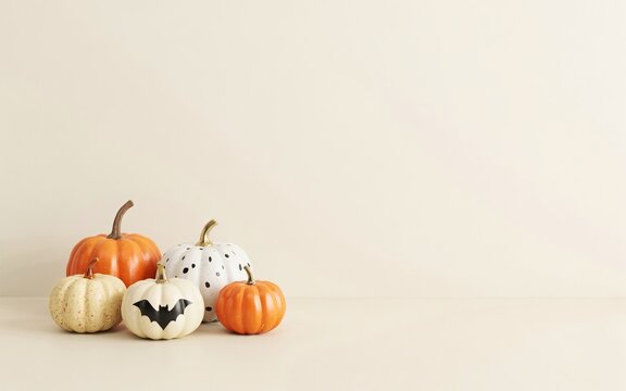 Four decorative pumpkins with bat and polka dot patterns on beige background
