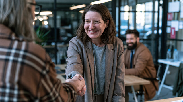 Happy businesswoman shaking hands greeting client in office