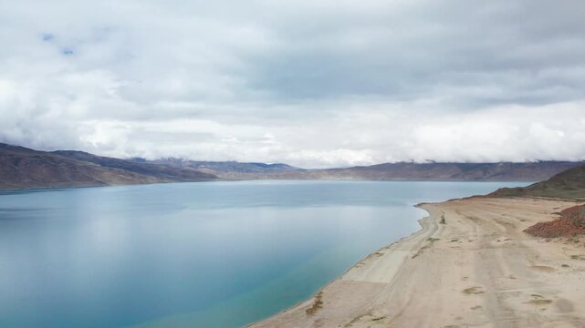 Drone view of Pegu Tso lake or Peikucuo in sunny day in Shigatse, Tibet, China, beautiful peaceful turquoise sea with mountains reflections in Xizang, 4k real time footage travel concept