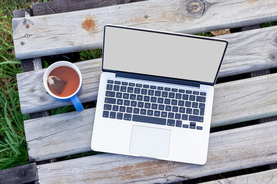 Top down view of a laptop mockup and a cup of tea on a rustic wooden deck