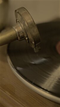 Vertical 4K video of a vintage vinyl record spinning on an antique gramophone with warm lighting and close-up detail.