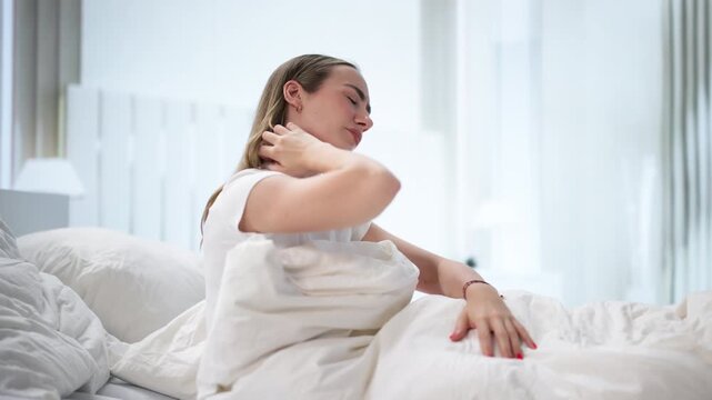 Young Woman Scratching Itchy Skin While Sitting On Bed