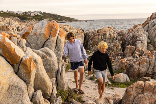 two barefoot boys exploring and hiking the spectacular rocky coastline of DeKeldres, South Africa