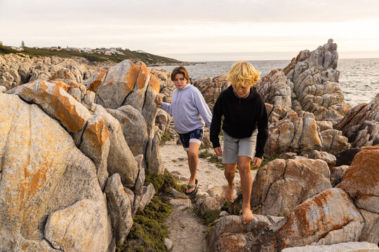 two barefoot boys exploring and hiking the spectacular rocky coastline of DeKeldres, South Africa