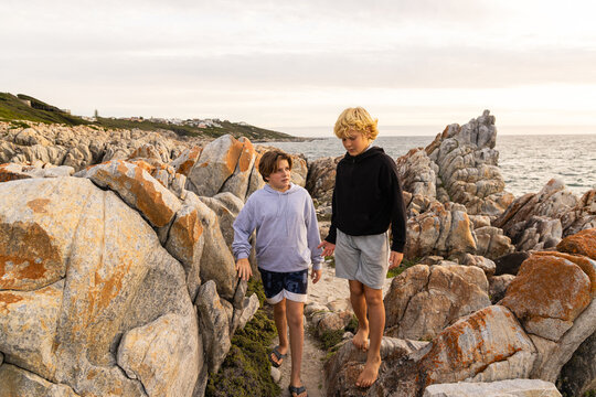 two barefoot boys exploring and hiking the spectacular rocky coastline of DeKeldres, South Africa