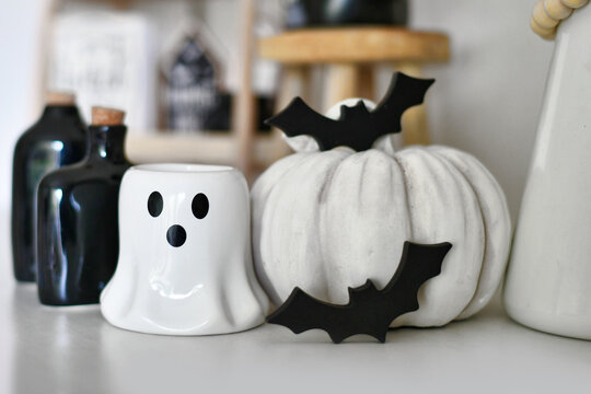 Black and white Halloween decoration with ghost shaped candle, pumpkin, wooden bats and potion bottles