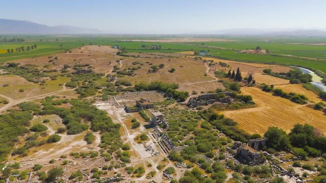 Balat, Turkey. Aerial drone view over the ancient ruins of Miletus, revealing the monumental Nymphaeum, Bouleuterion council house, and North Agora colonnades amid sunlit archaeological parklands. Ae