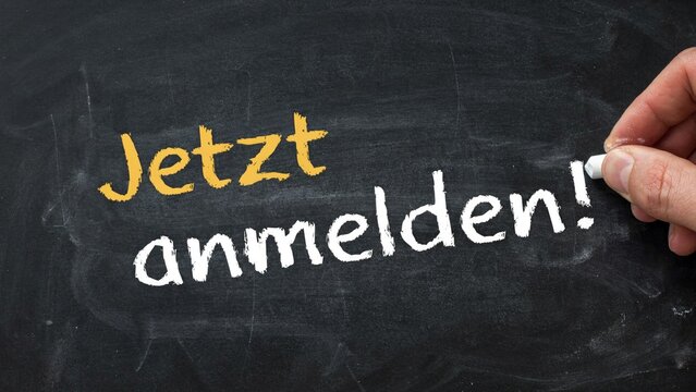 Hand writing Jetzt anmelden on blackboard, chalk text, sign, education concept, german words
