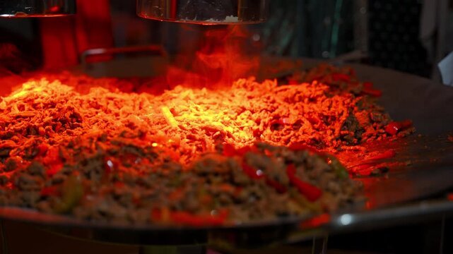 Freshly cooked stir fried noodles with seasoned beef and vegetables on a large catering flat-top grill.