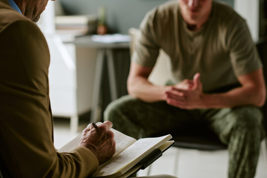 Young adult man in military hospital receiving counseling session, discussing recovery and mental health support with clinician. Useful for veteran care, trauma therapy, rehabilitation marketing