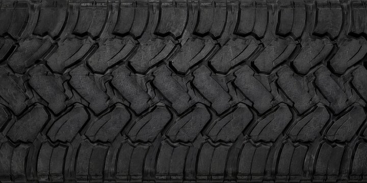 High-resolution close-up of a large black truck tire tread texture featuring deep rugged grooves and durable rubber patterns.
