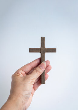 Hand holding a wooden crucifix cross. Isolated on light background.