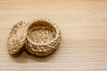 Obraz premium Open Single Round Hand Woven Straw Basket with Lid on Light Wood Surface