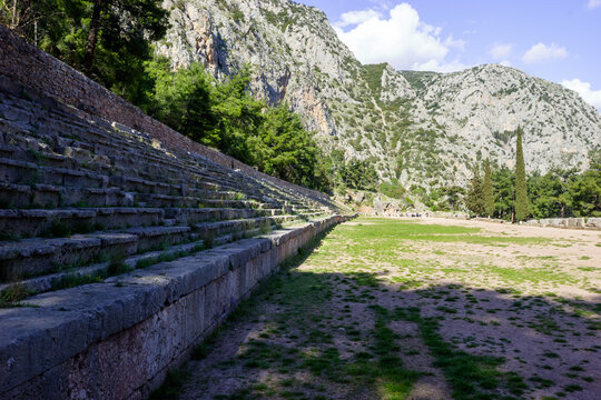A group of tourists visits the ancient theater of Delphi, Greece, on a sunny day.